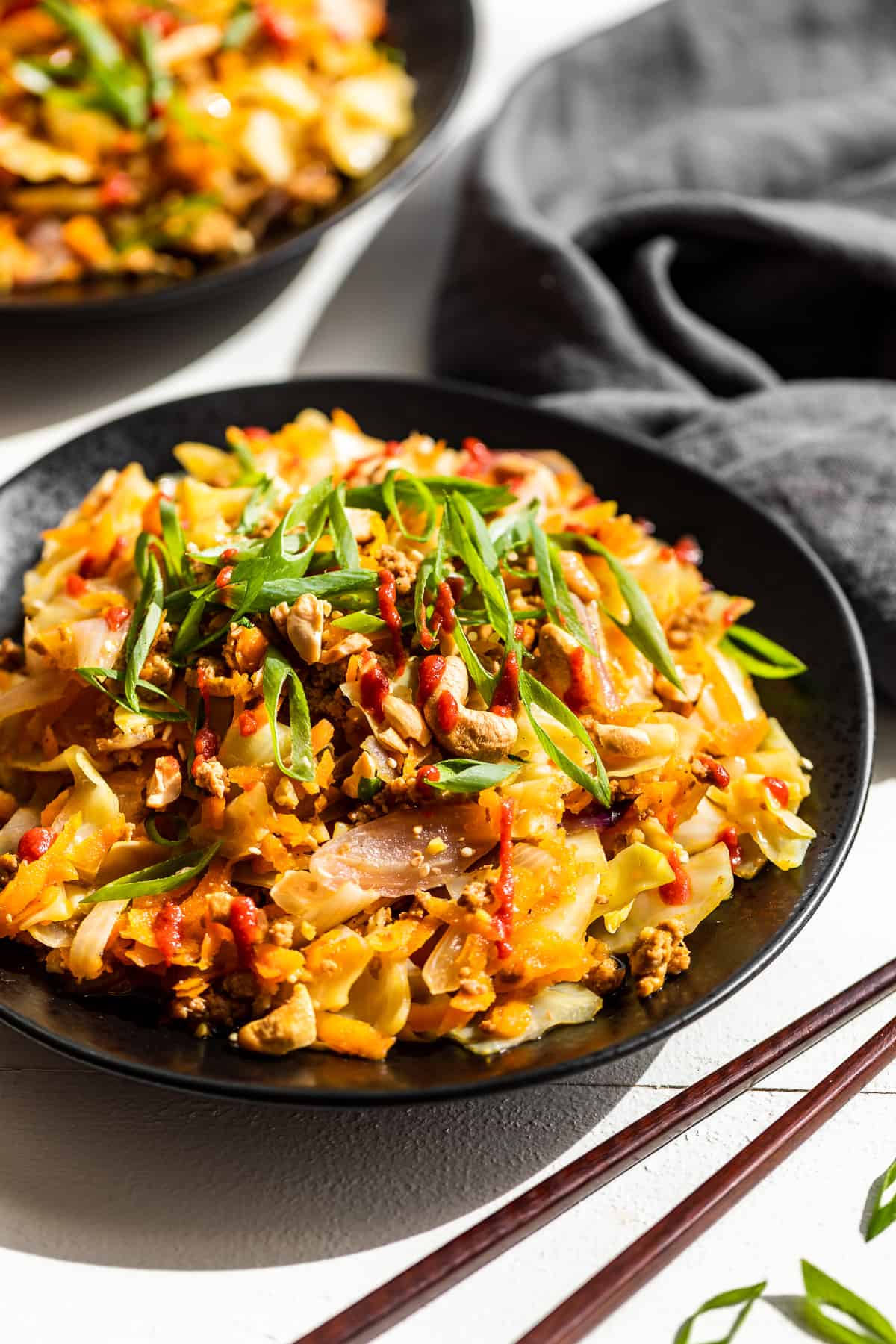 Side view of 2 plates of egg roll bowl with chopsticks on the side.