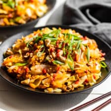 2 black plates of finished Egg Roll Bowl topped with green onions and cashews.