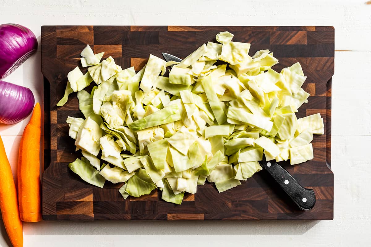 Chopped up cabbage on a wooden cutting board.