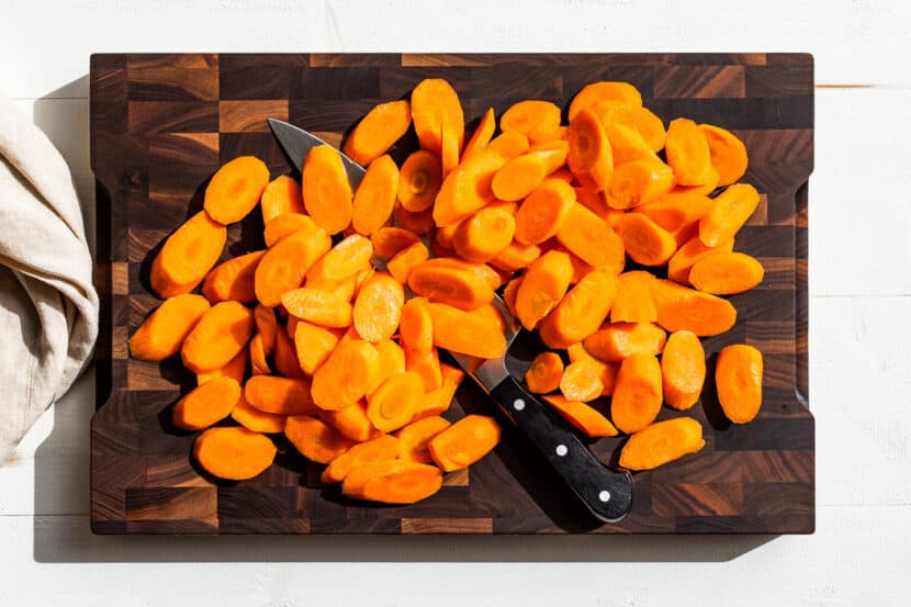 Sliced up carrots on a wooden cutting board.