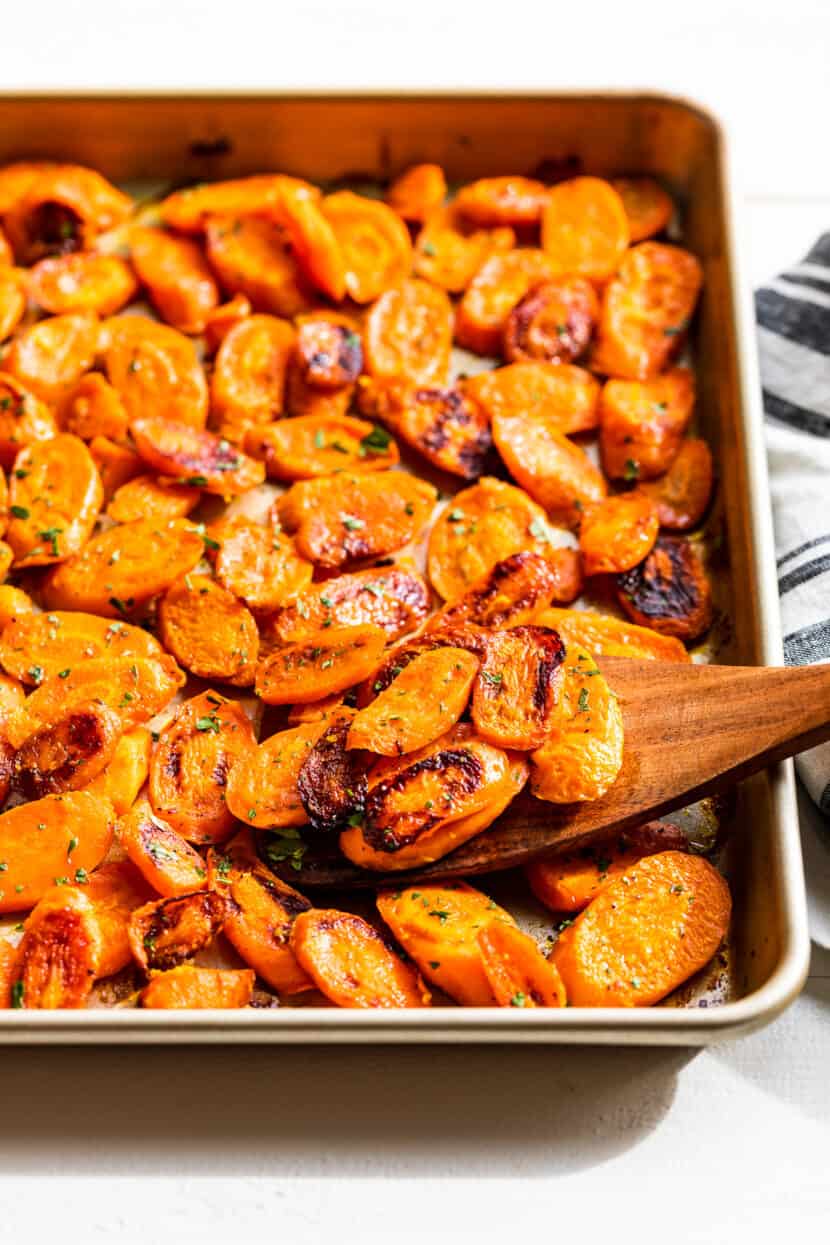 Side view of Roasted Carrots in a sheet pan on a white background.