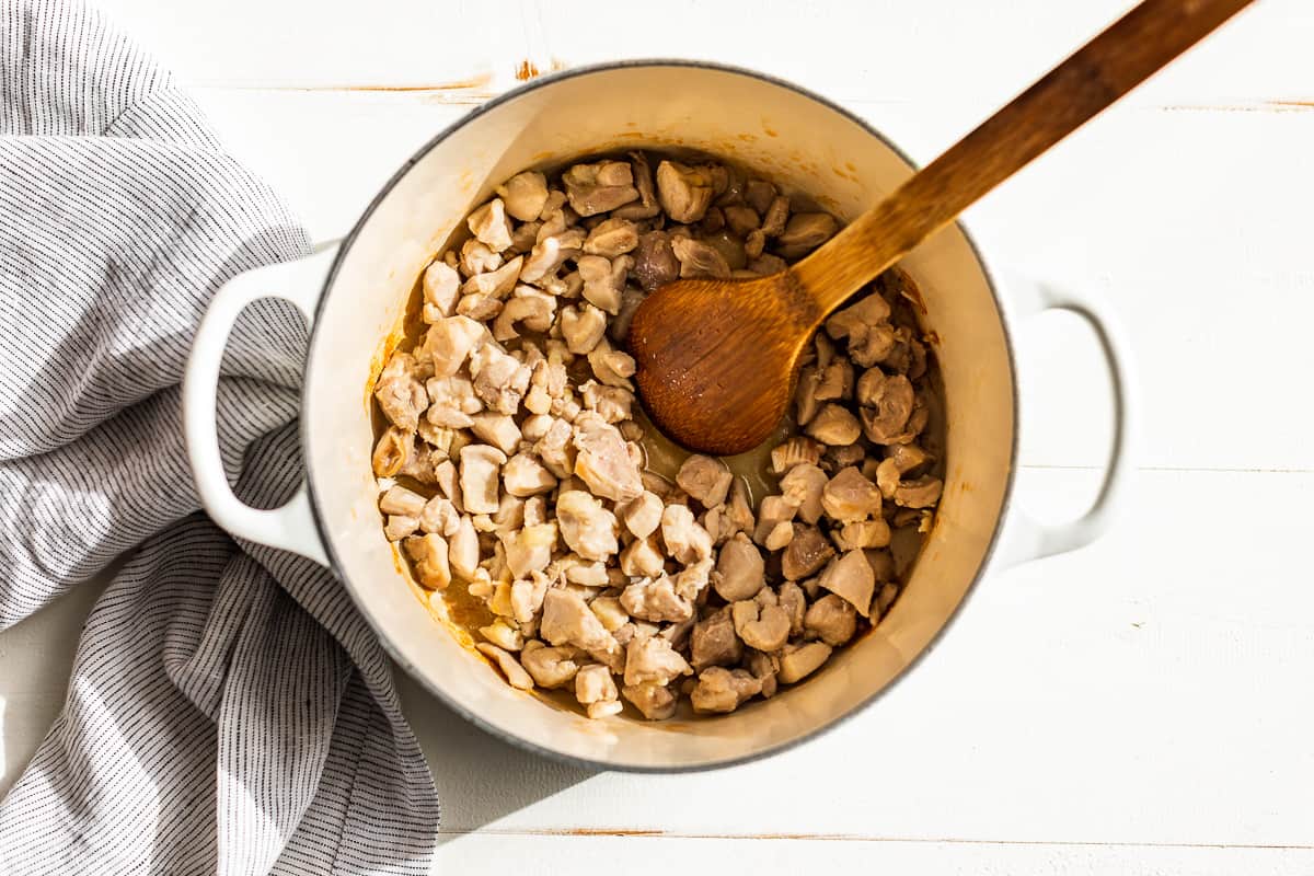 Sautéed chicken in a white pot.