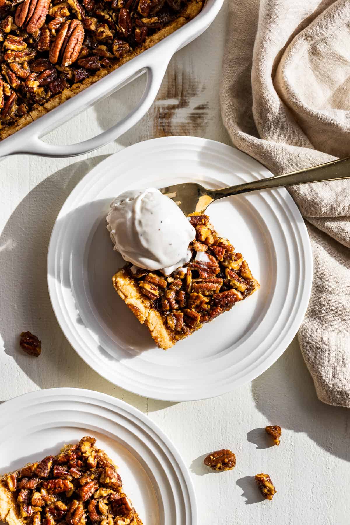 Two plates of pecan pie bars with a scoop of vanilla ice cream on top.