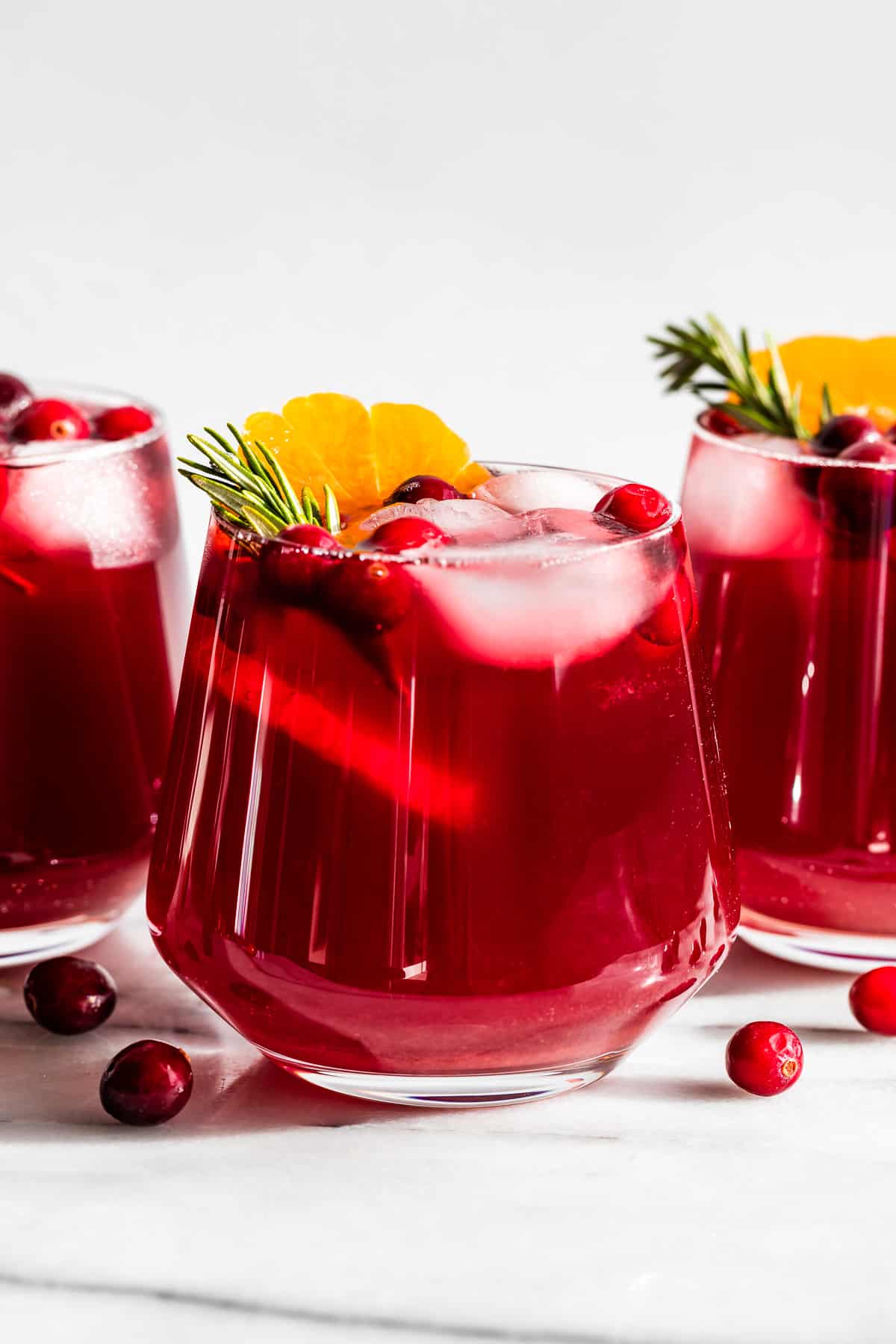 Straight on view of Cranberry Kombucha Mocktail in a glass with an orange slice in it.