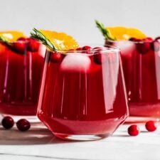 Side view Cranberry Kombucha Mocktails with cranberries around the glasses.