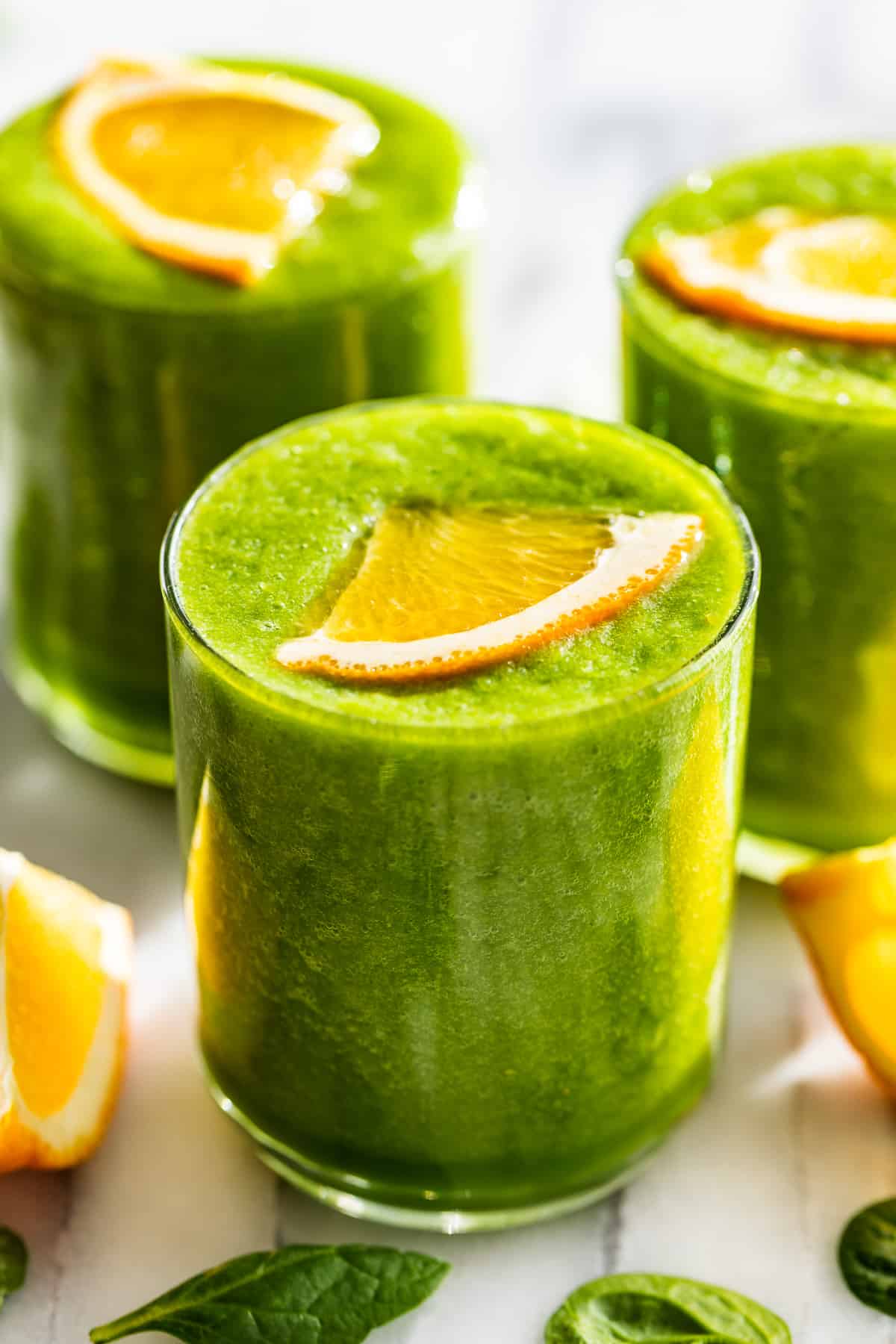 Side view of Detox Green Smoothie glasses with orange slices on top.