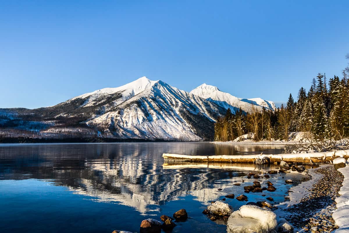 Mountain with a reflection in the lake with tress along the shoreline.