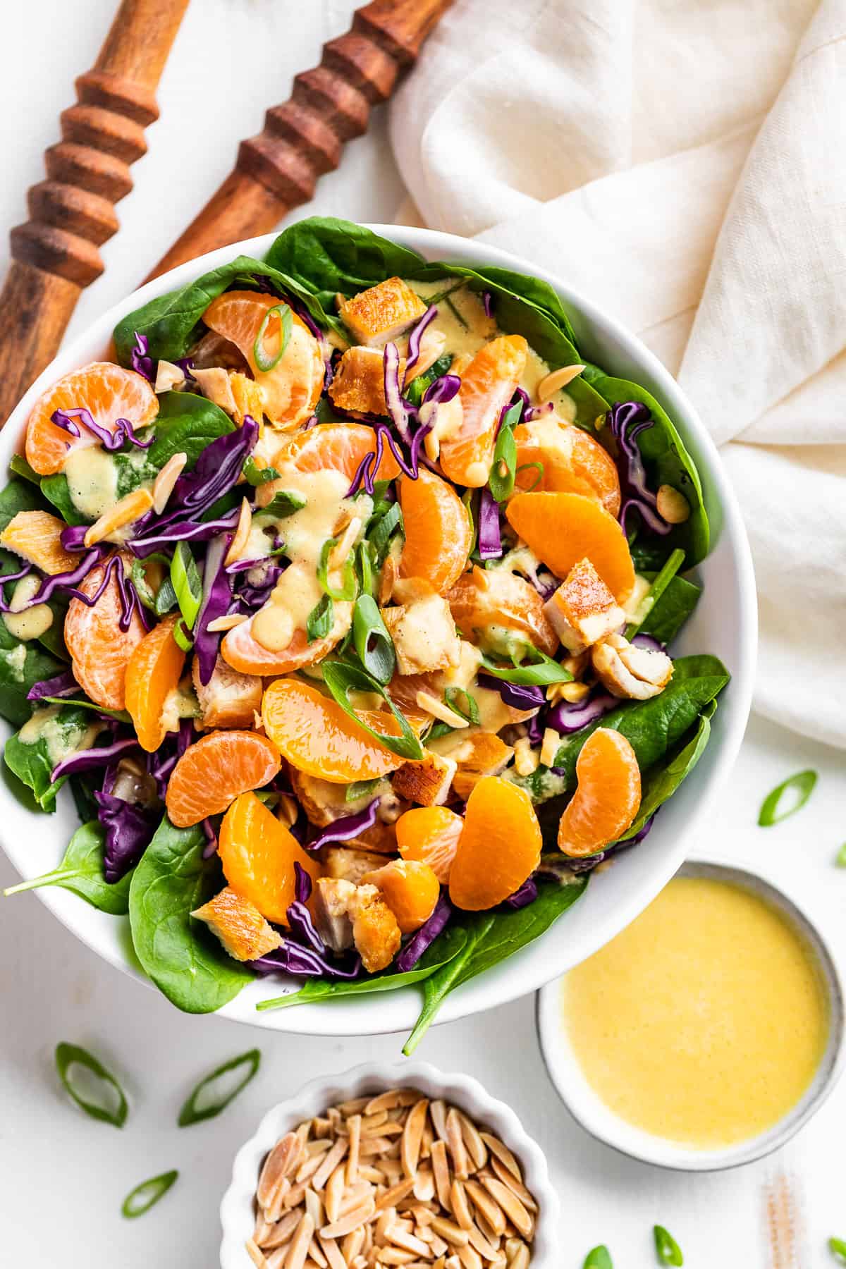 Downward view of Mandarin Chicken Salad with wooden serving spoons on the side.