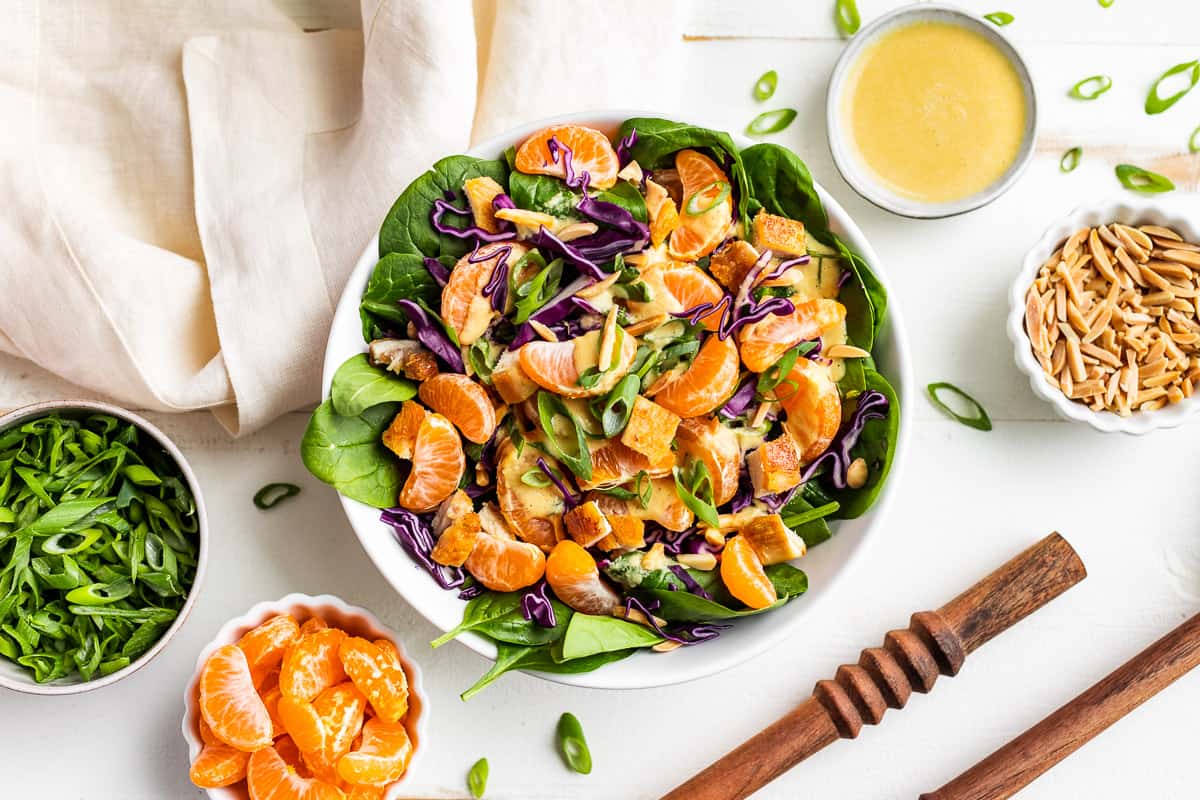 Mandarin Chicken Salad in a white bowls with extra garnishes around it.