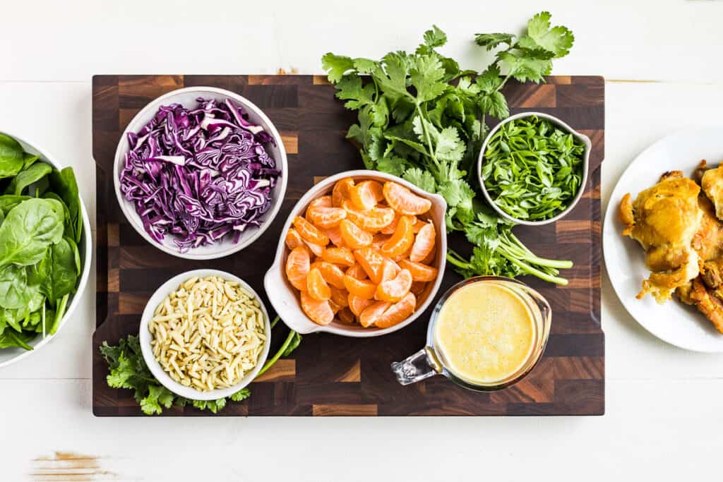 All the prepped salad ingredients on a wooden cutting board.