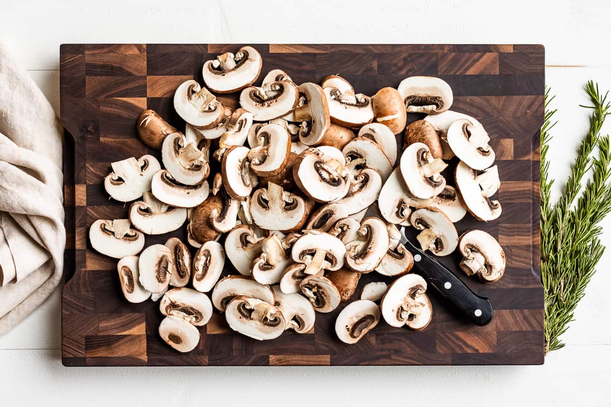 Sliced mushrooms on a wooden cutting board.
