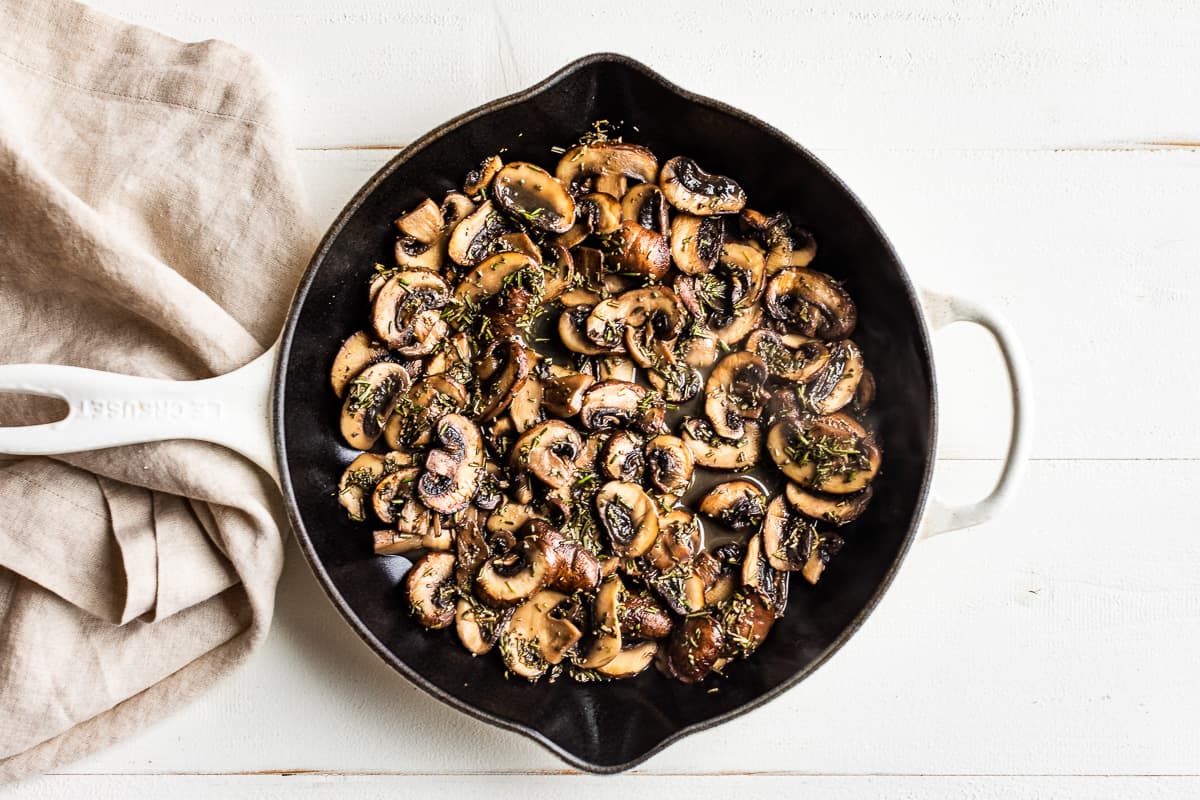 Adding the white wine and rosemary to the sautéed mushrooms.