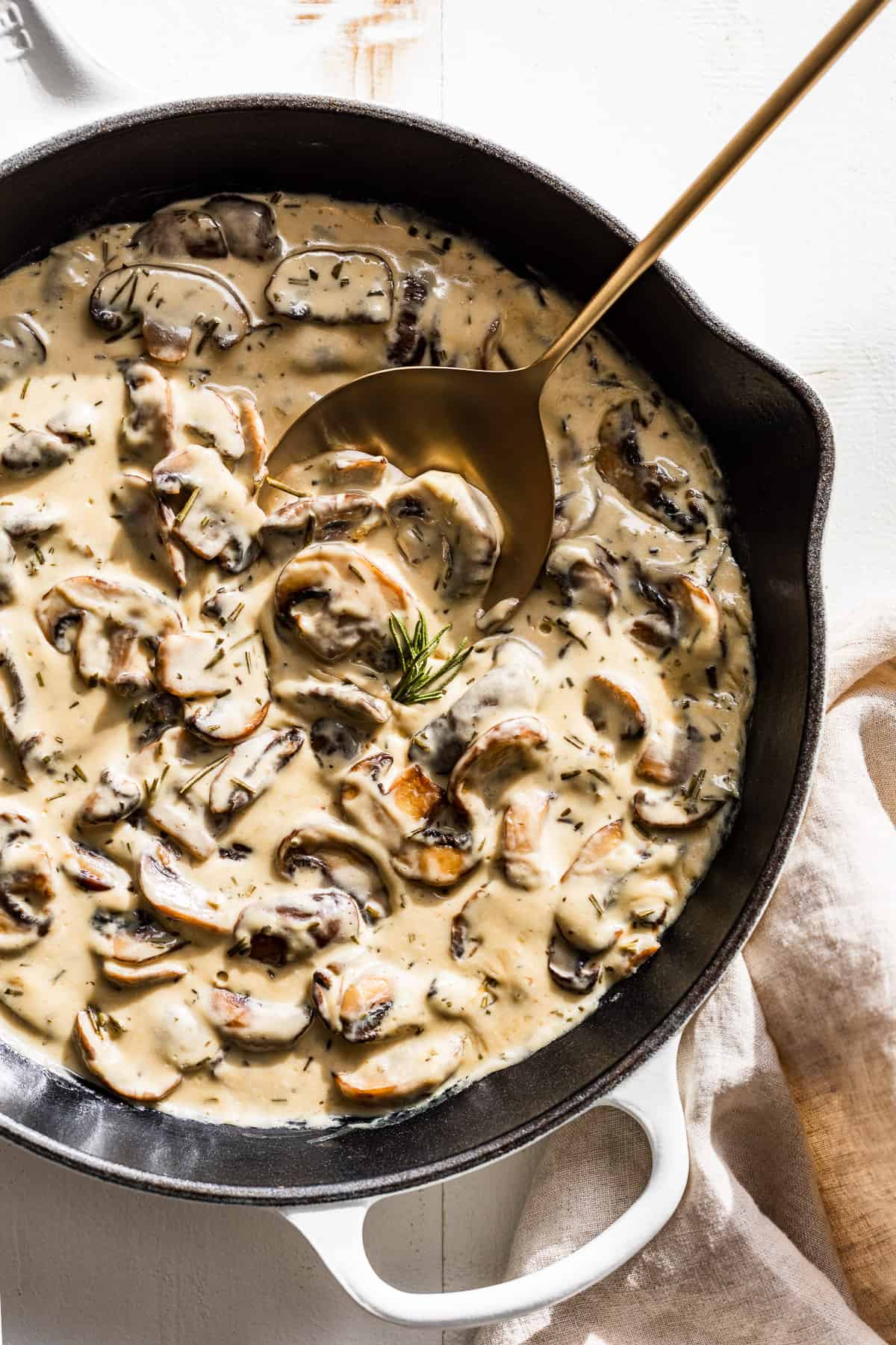 White skillet with Mushroom Cream Sauce and a gold spoon.