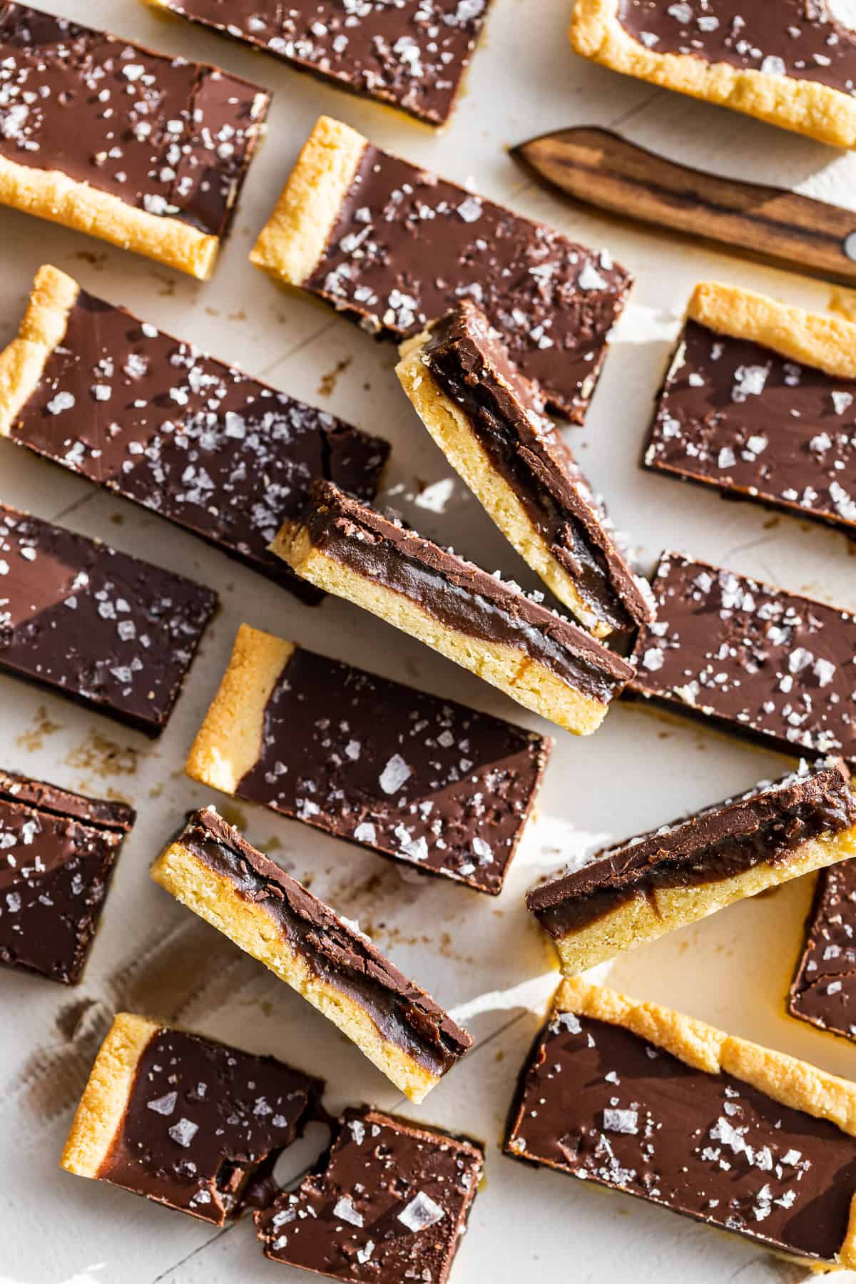 Paleo Twix Bars on a white background with some turned sideways showing the caramel filling.
