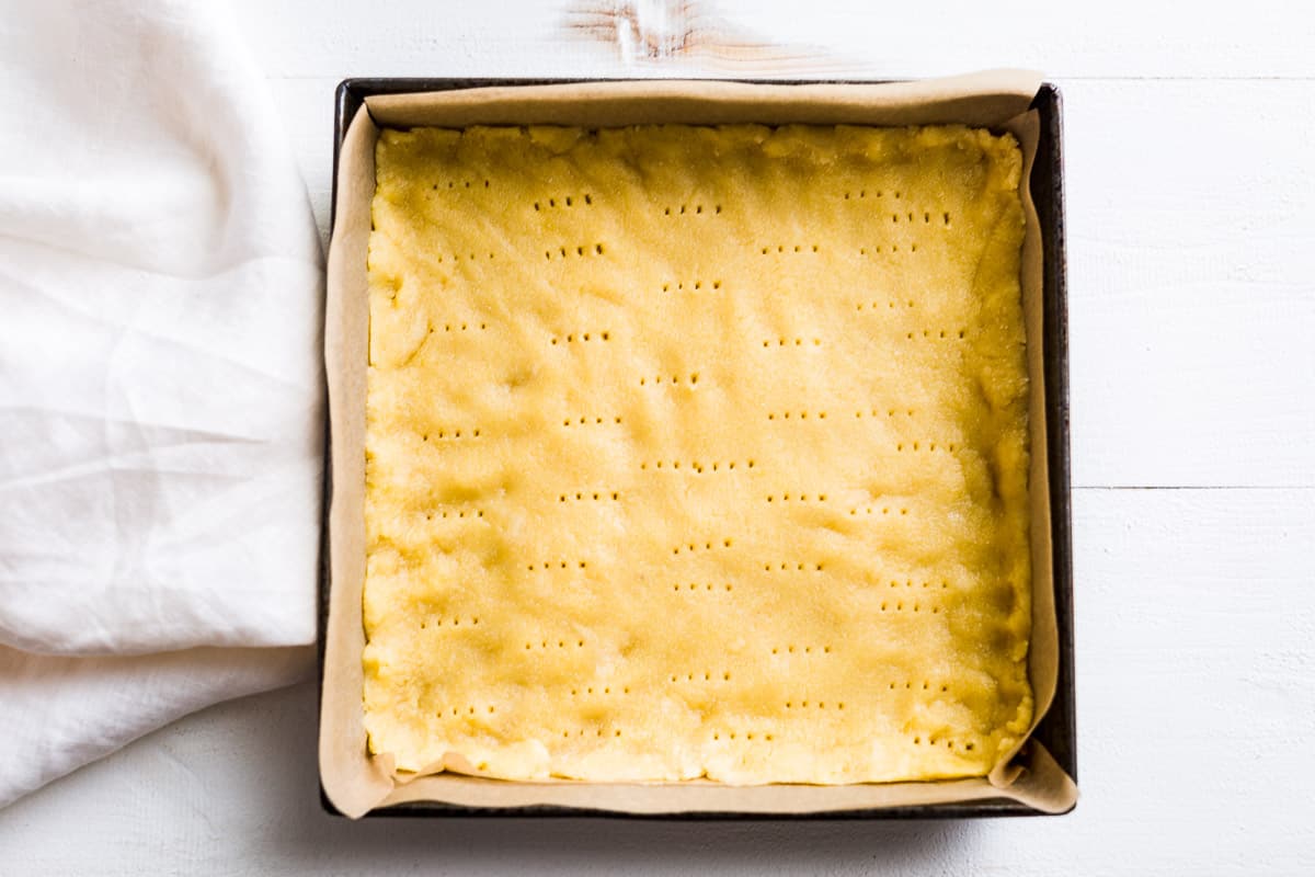 The shortbread crust patted out into a parchment lined 8" baking pan.