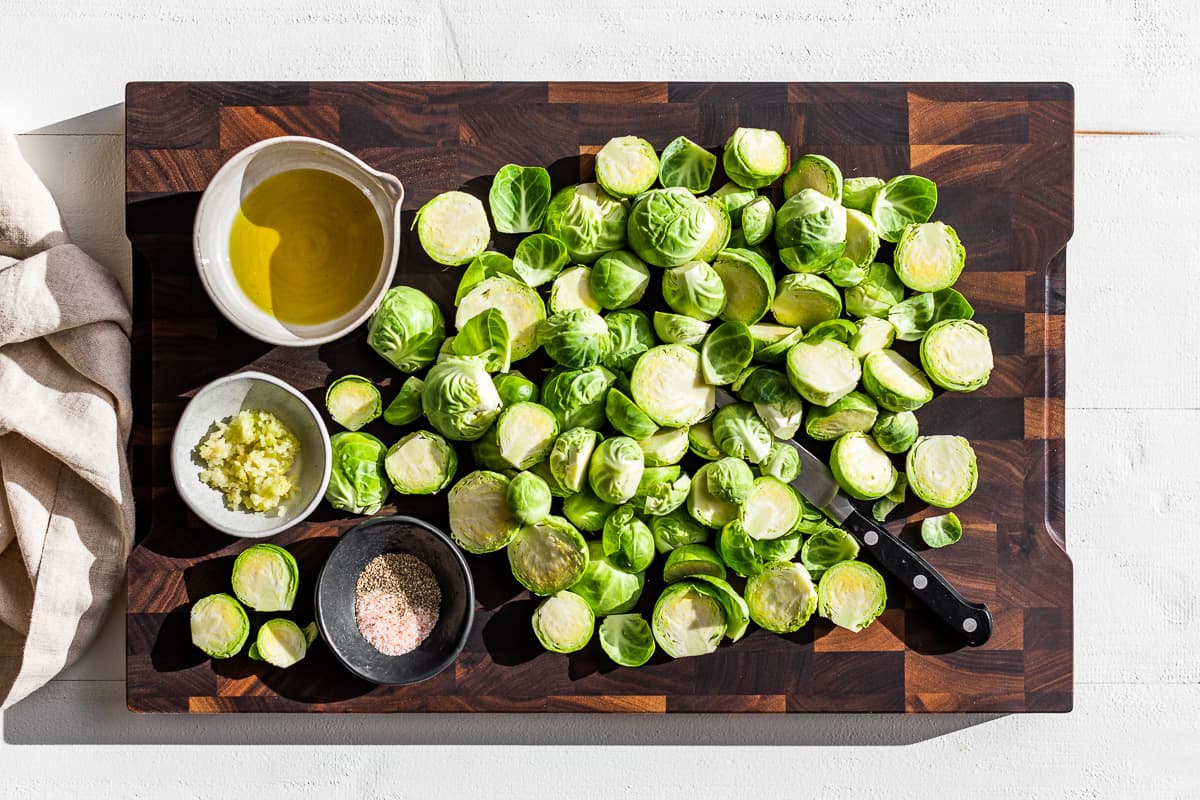 Halved Brussels sprouts on a wooden cutting board.