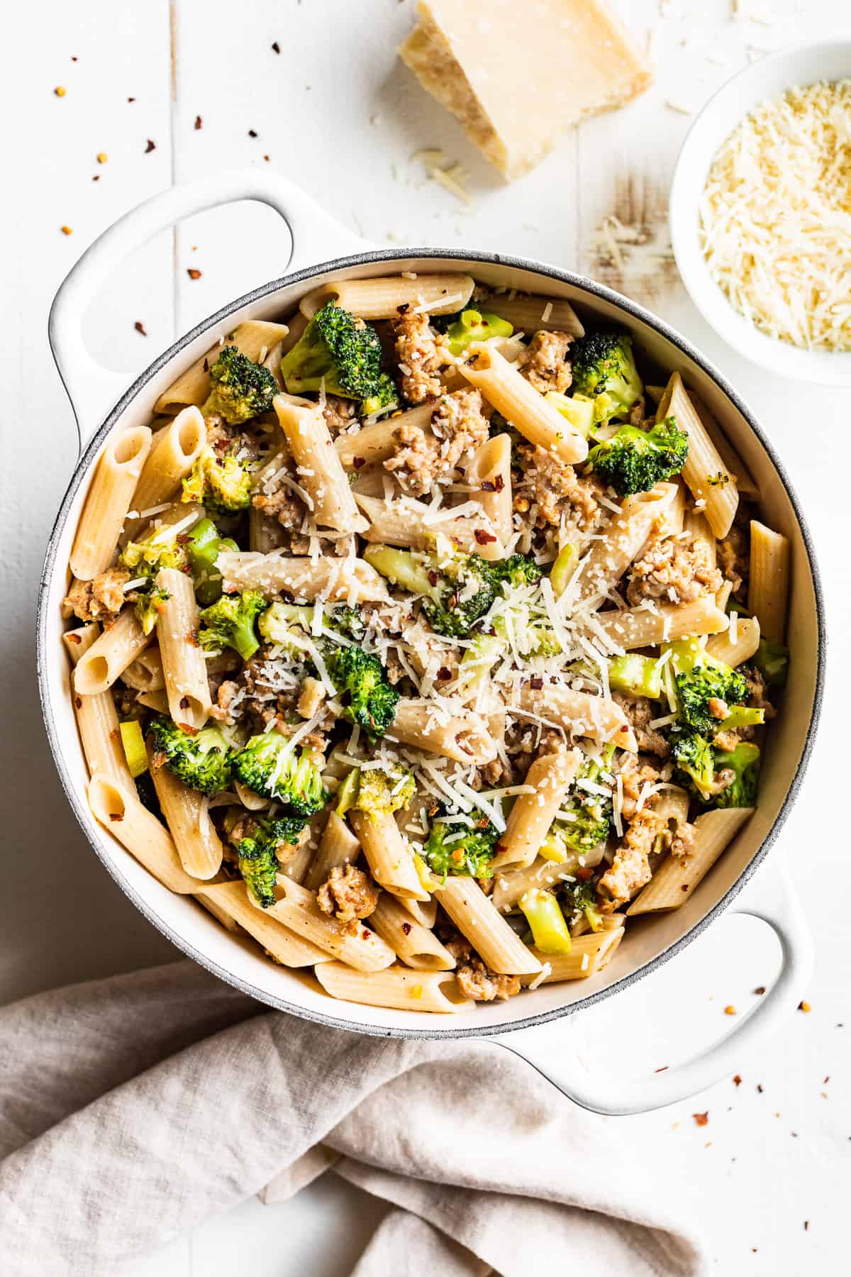 Straight down view of Sausage Broccoli Pasta with grated Parmesan cheese in a white bowl on the side.