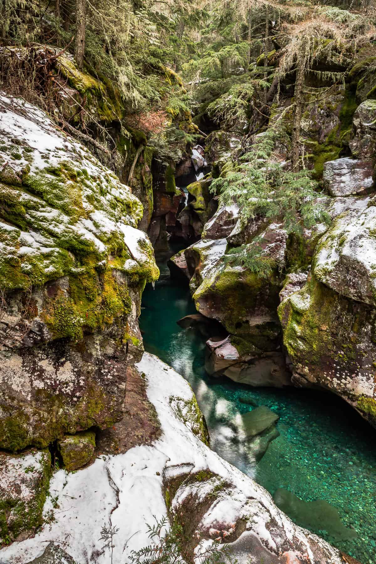 Turquoise water in a gorge with snow on the rocky sides.