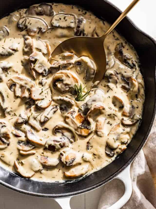 White skillet with Mushroom Cream Sauce and a gold spoon.