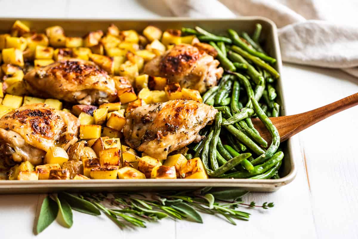 Finished Garlic Butter Chicken with potatoes and green beans on a cookie sheet.