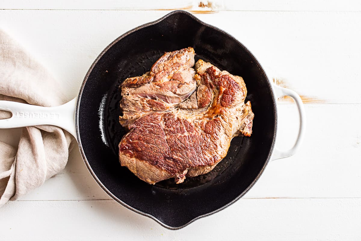 Seared beef roast in a large cast iron skillet.