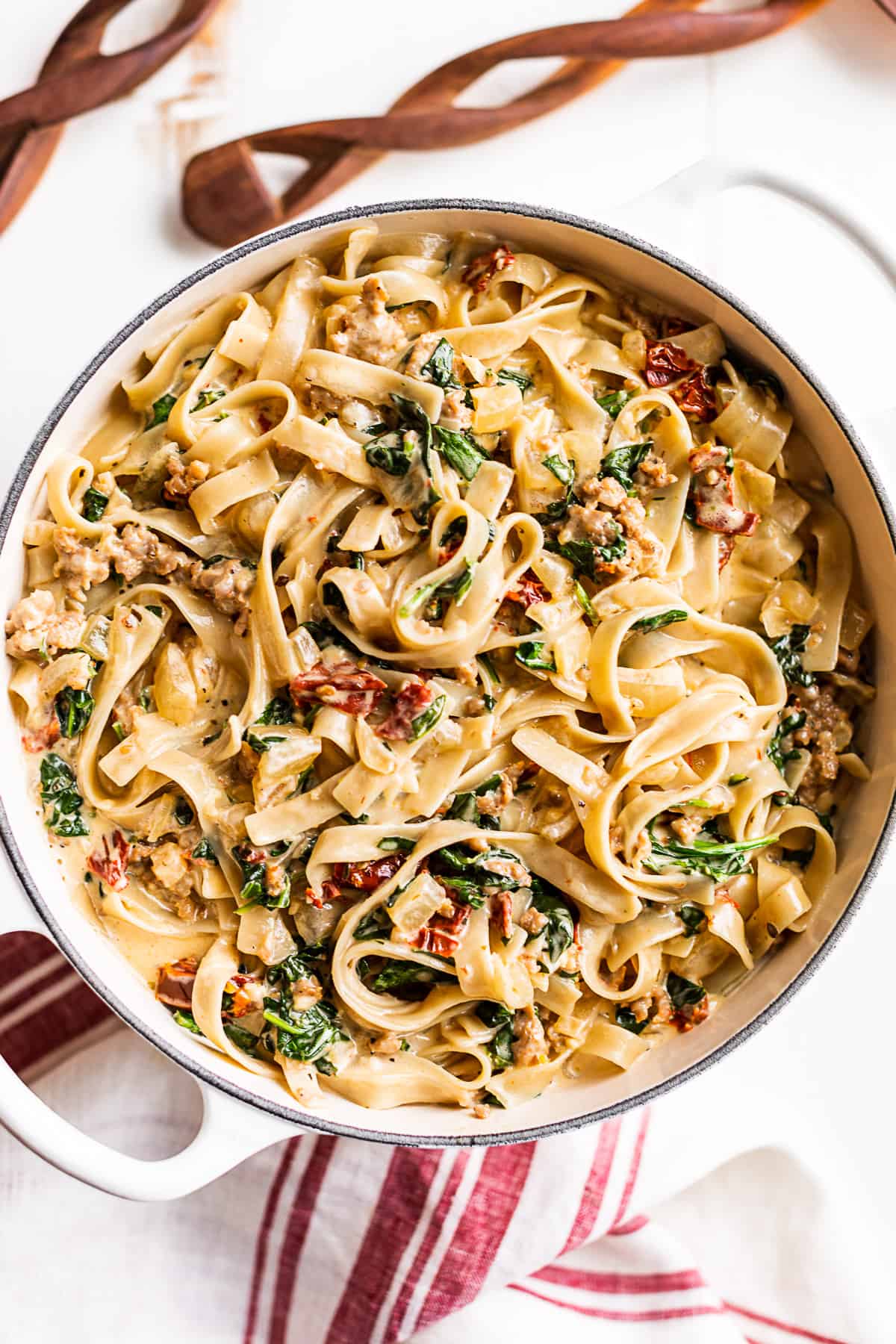 Straight down view of the Tuscan Sausage Pasta made with fettucine with wooden spoons on the side.