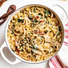 Finished Tuscan Sausage Pasta with a red and white striped linen on the side.