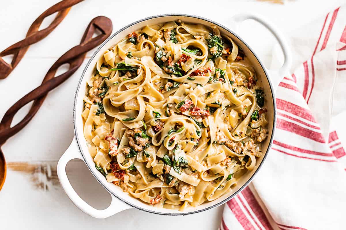 Finished Tuscan Sausage Pasta with a red and white striped linen on the side.