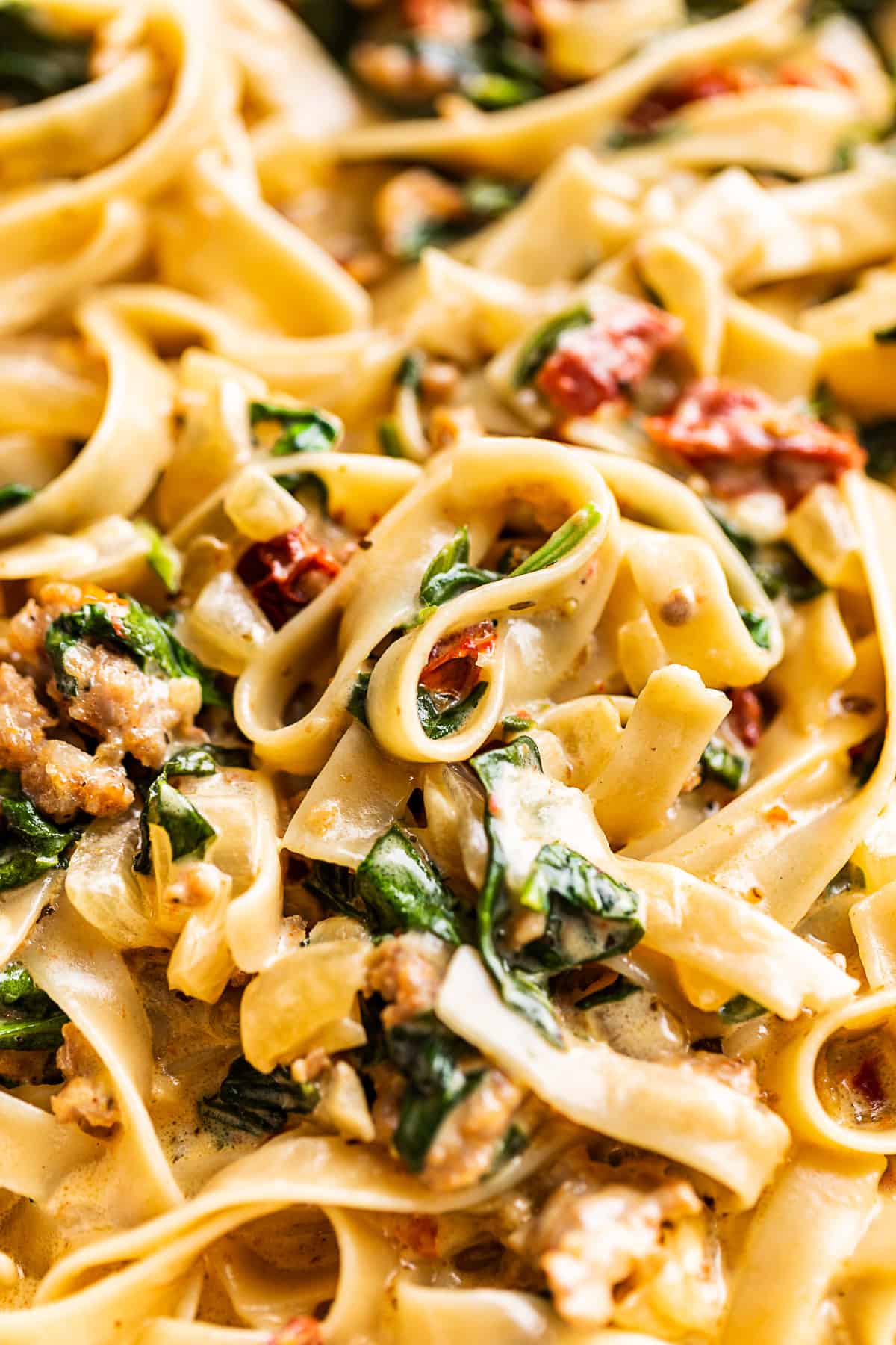 A close up view of Tuscan Sausage Pasta with twirled fettucine pasta.