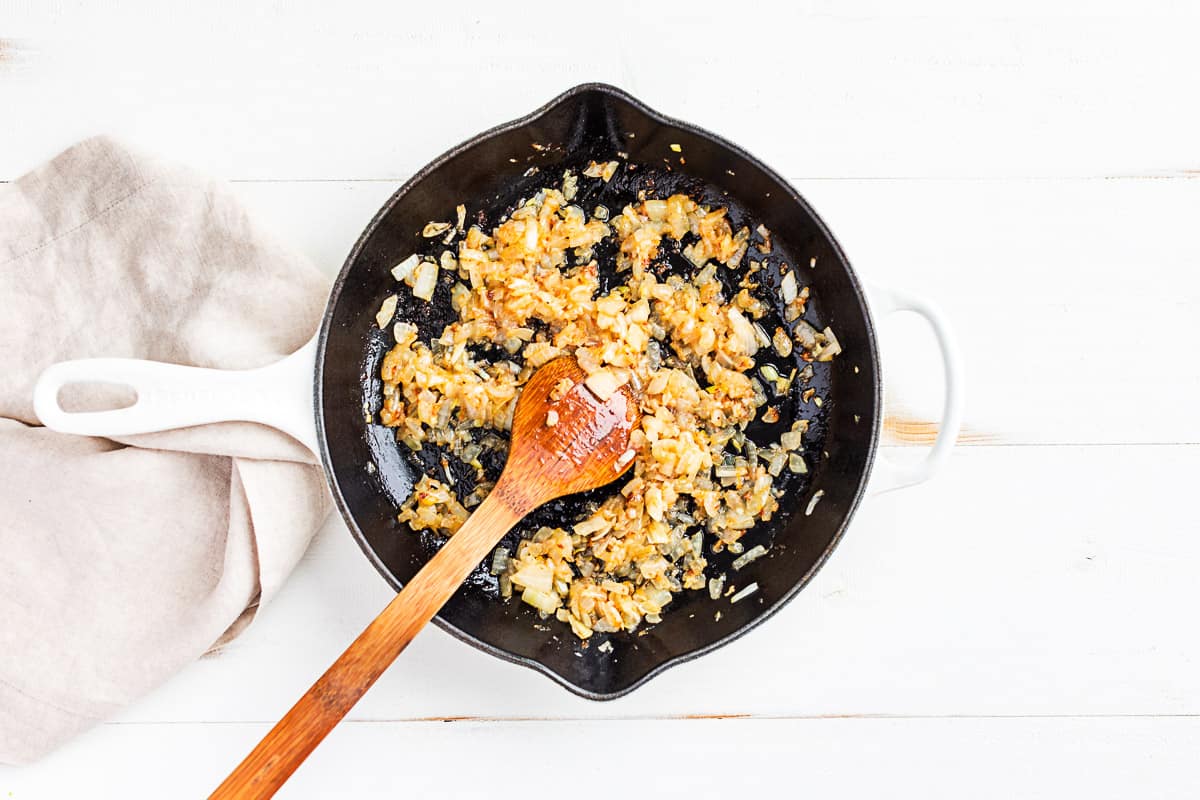 Sautéed onions in a large white cast iron skillet.