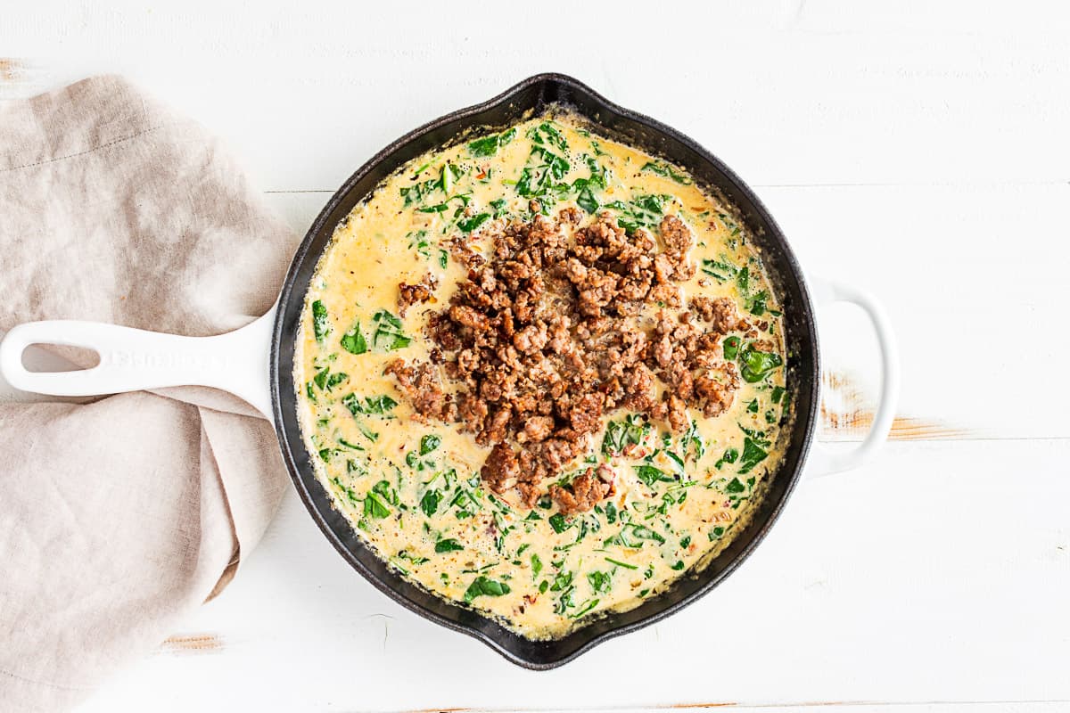 Adding the browned Italian sausage to the finished cream sauce.