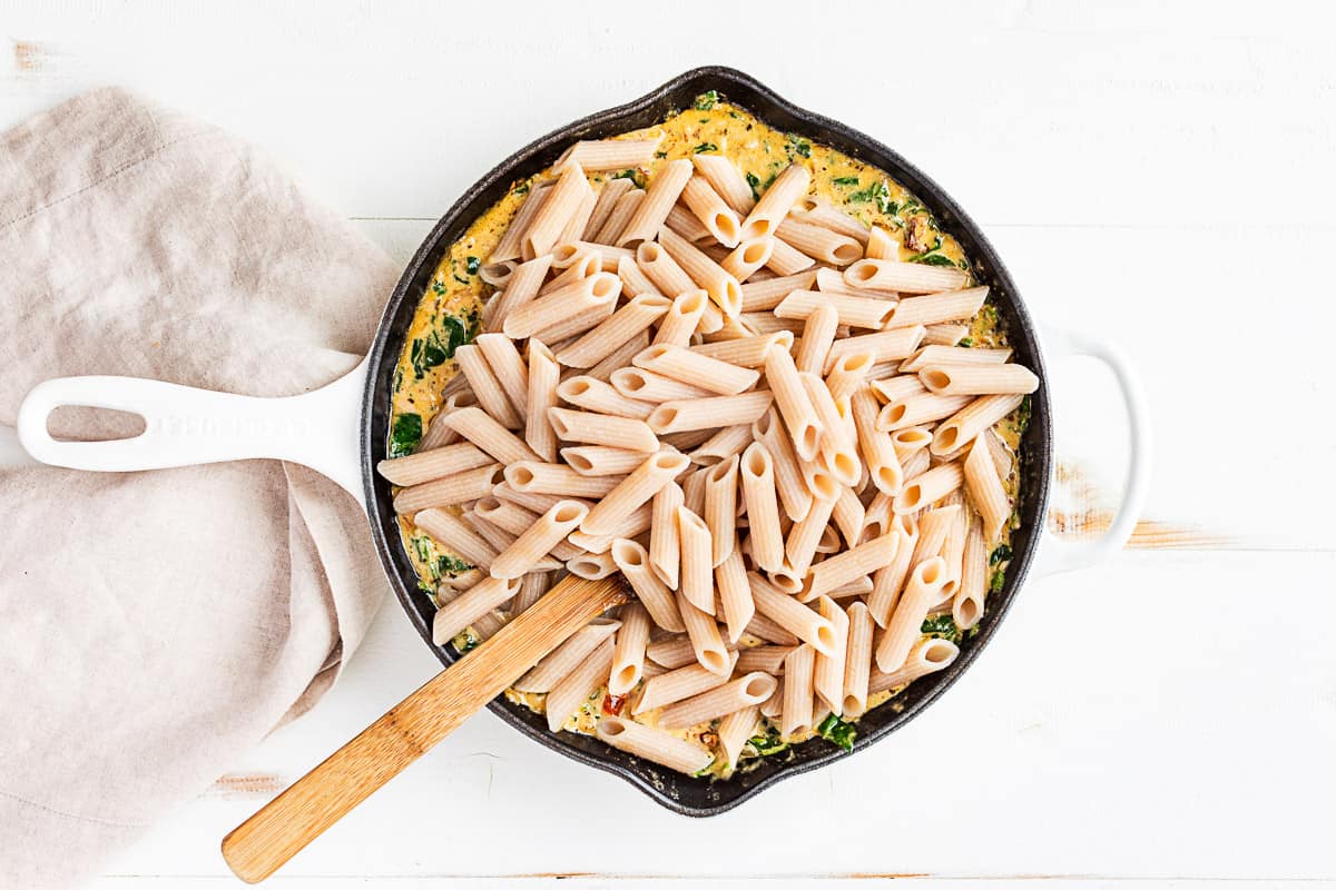 Adding the cooked pasta to the finished cream sauce.