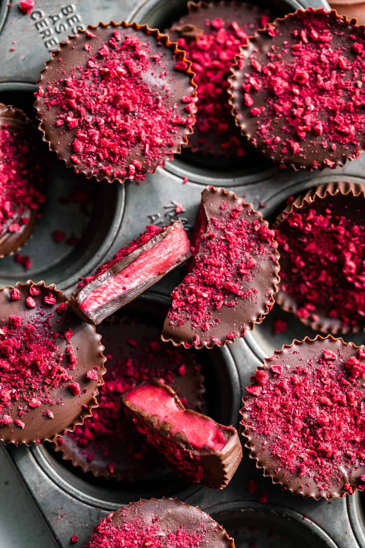 Chocolate Raspberry Candies in a vintage muffin tin with two cut open to see the filling.