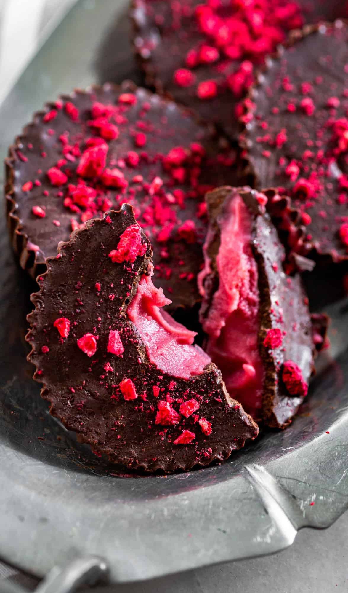 A silver tray filled with Chocolate Raspberry Candies with one split in half.