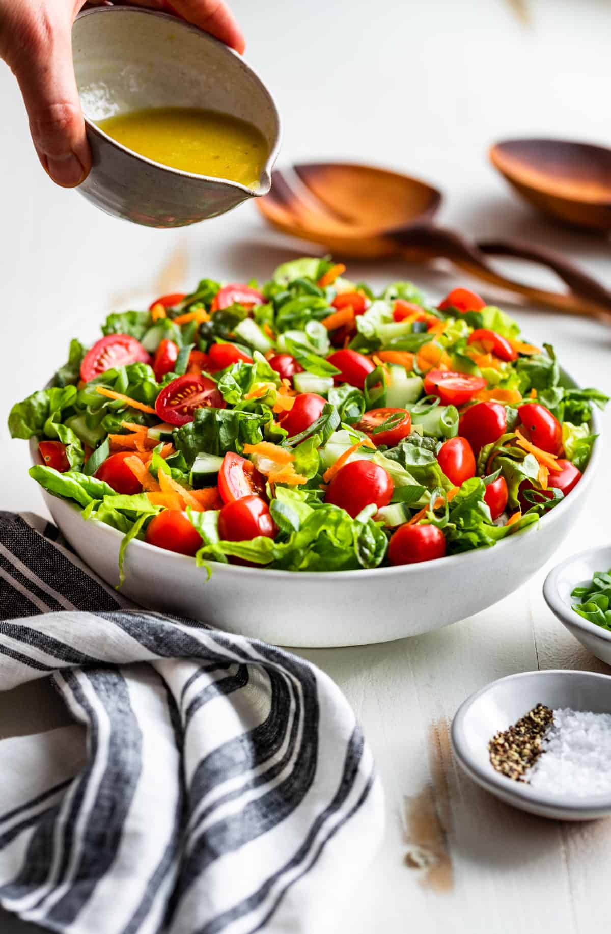 Lemon vinaigrette about to be poured over the green salad.