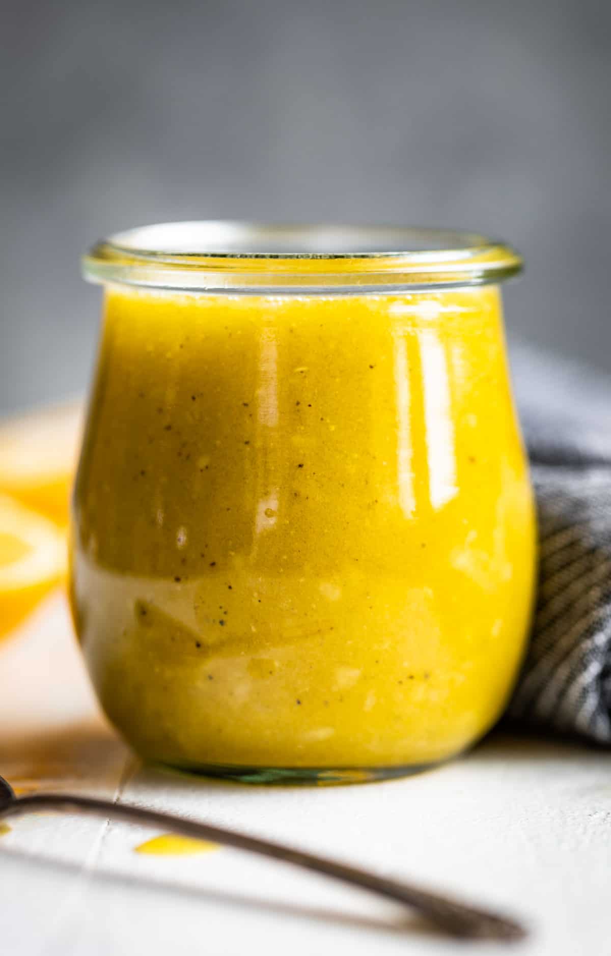 Lemon Vinaigrette in a glass jar with a silver spoon on the side.