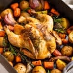 Side view of finished Roasted Chicken and Vegetables in a grey roaster pan.