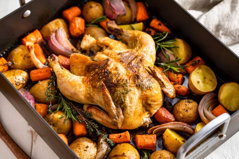 Side view of finished Roasted Chicken and Vegetables in a grey roaster pan.