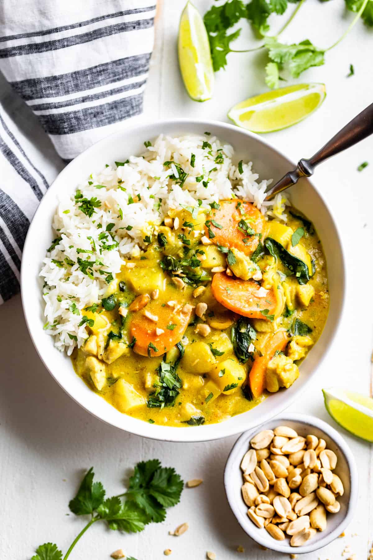 Straight down view of a white bowl with steamed rice and yellow curry with chopped cilantro on top.