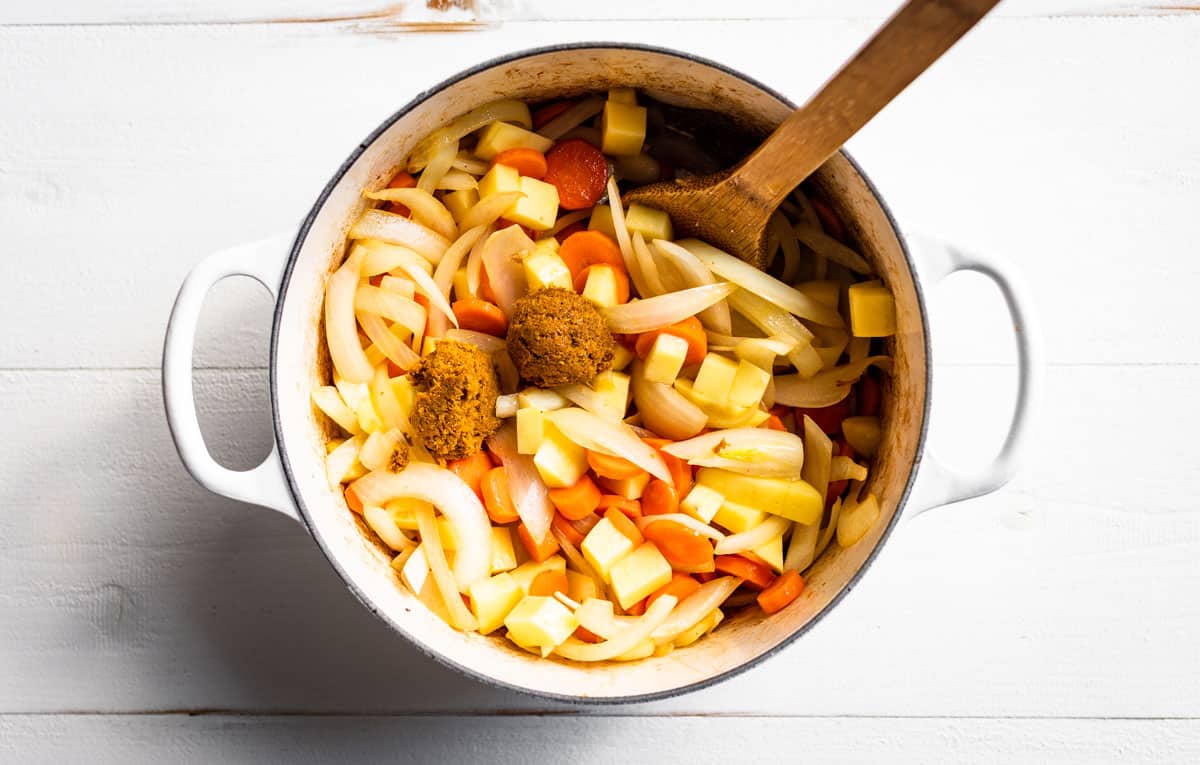 Sautéed onions, carrots, and potatoes with the curry paste being added.