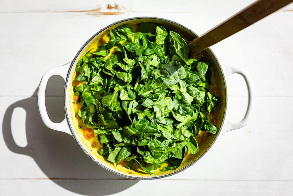 Adding the chopped spinach to the curry.