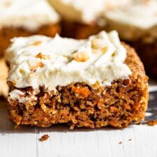 Three slices of carrot cake topped with cream cheese frosting.