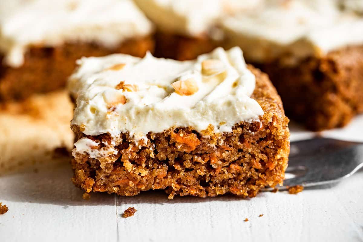 Three slices of carrot cake topped with cream cheese frosting.