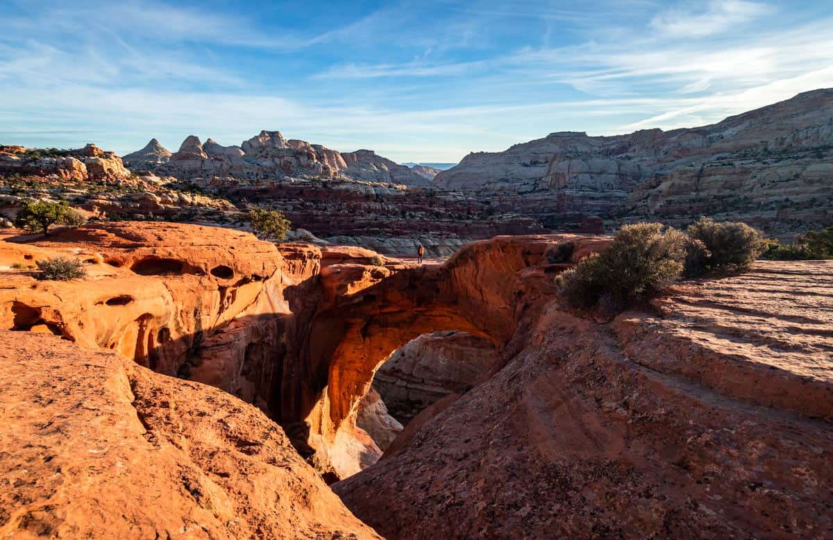 Man standing on Cassidy Arch in Capitol Reef at sunrise.