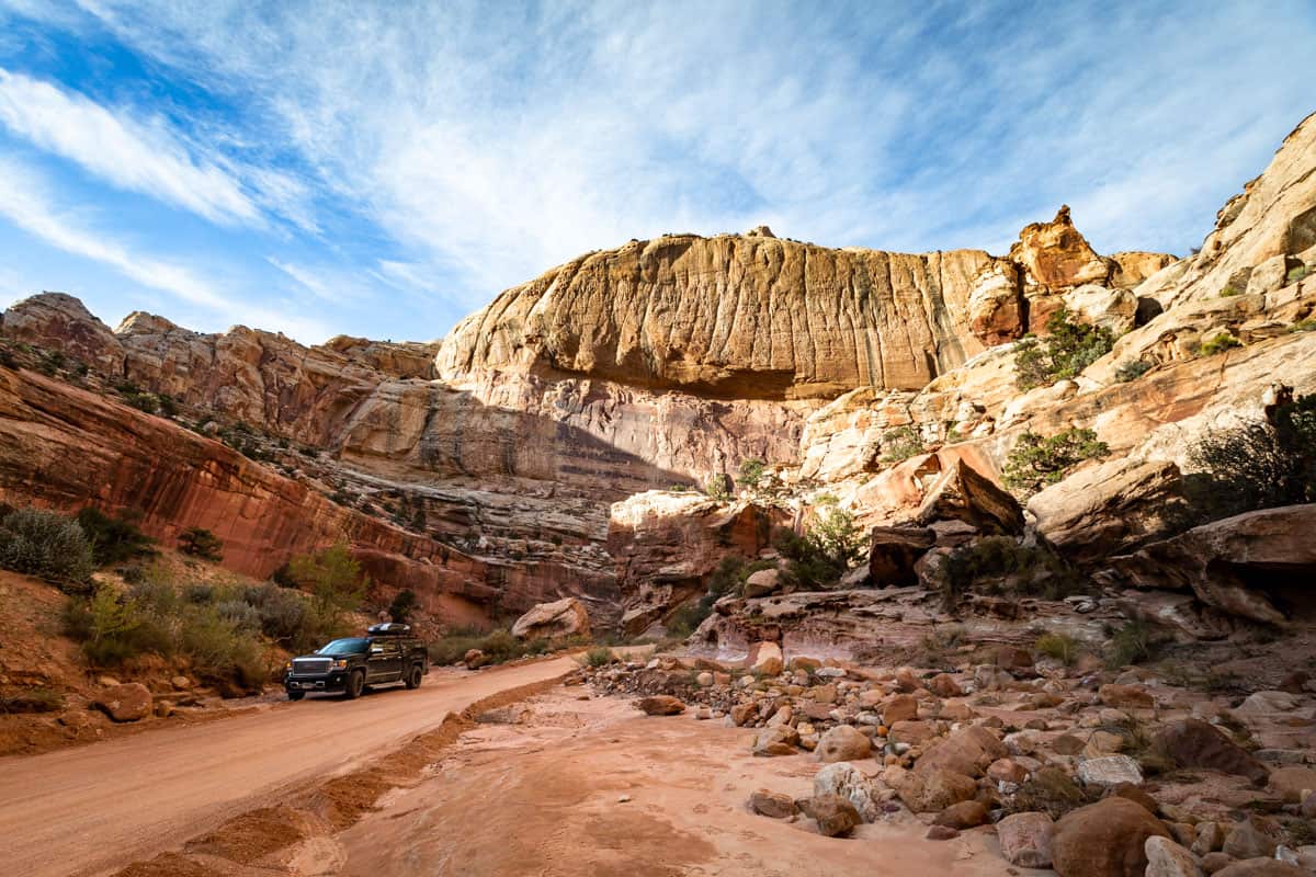 The view from the dirt road portion, Capitol Gorge Road, of the scenic drive in Capitol Reef with a black truck parked on the side of the road.