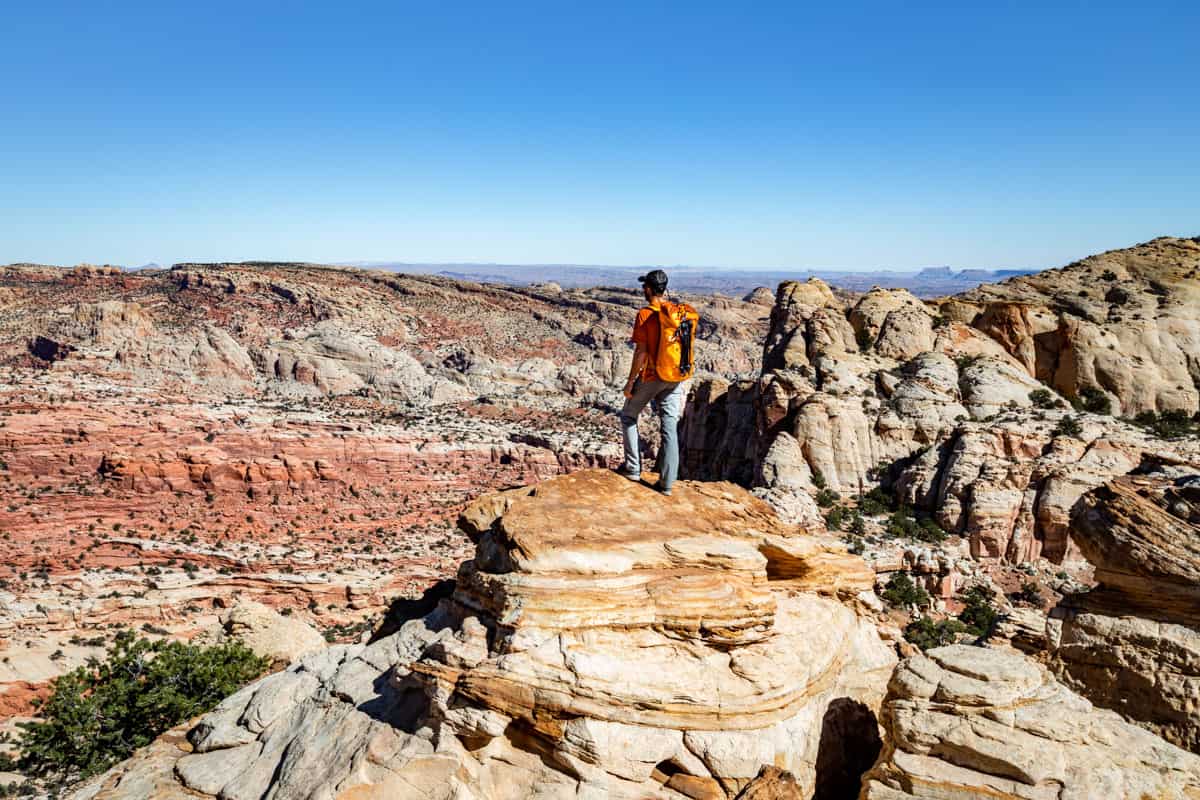 Man standing on top of the Navajo Knobs looking over the valleys of Capitol Reef.