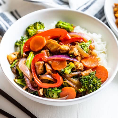 Two white bowls of Chicken Stir Fry with chopsticks next to the front bowl.