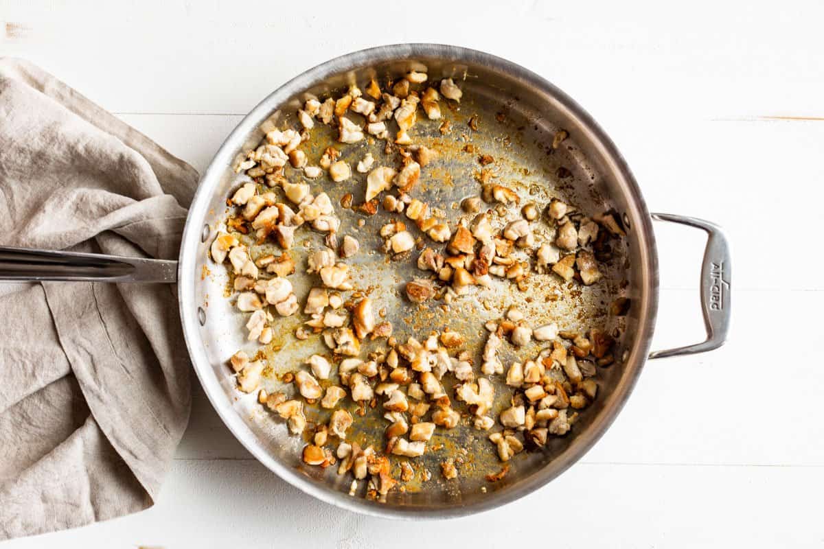 Sautéing the chicken in a large frying pan.