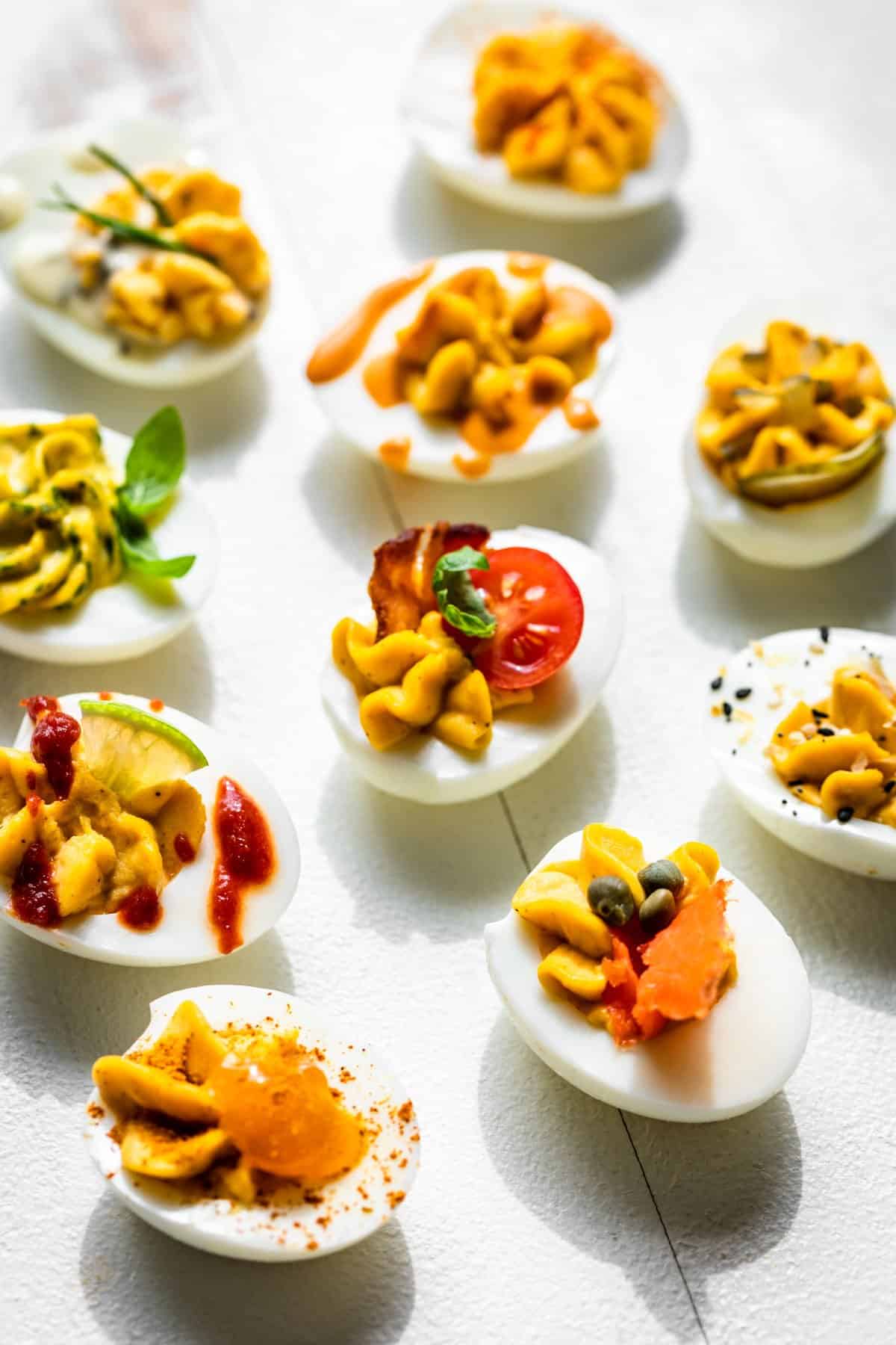 Side view of all ten deviled eggs flavors on a white background.