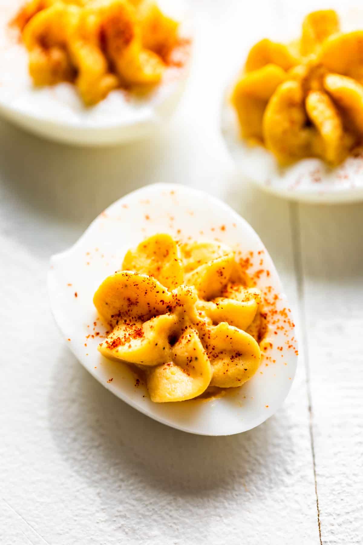 Classic deviled eggs on a white background sprinkled with paprika.